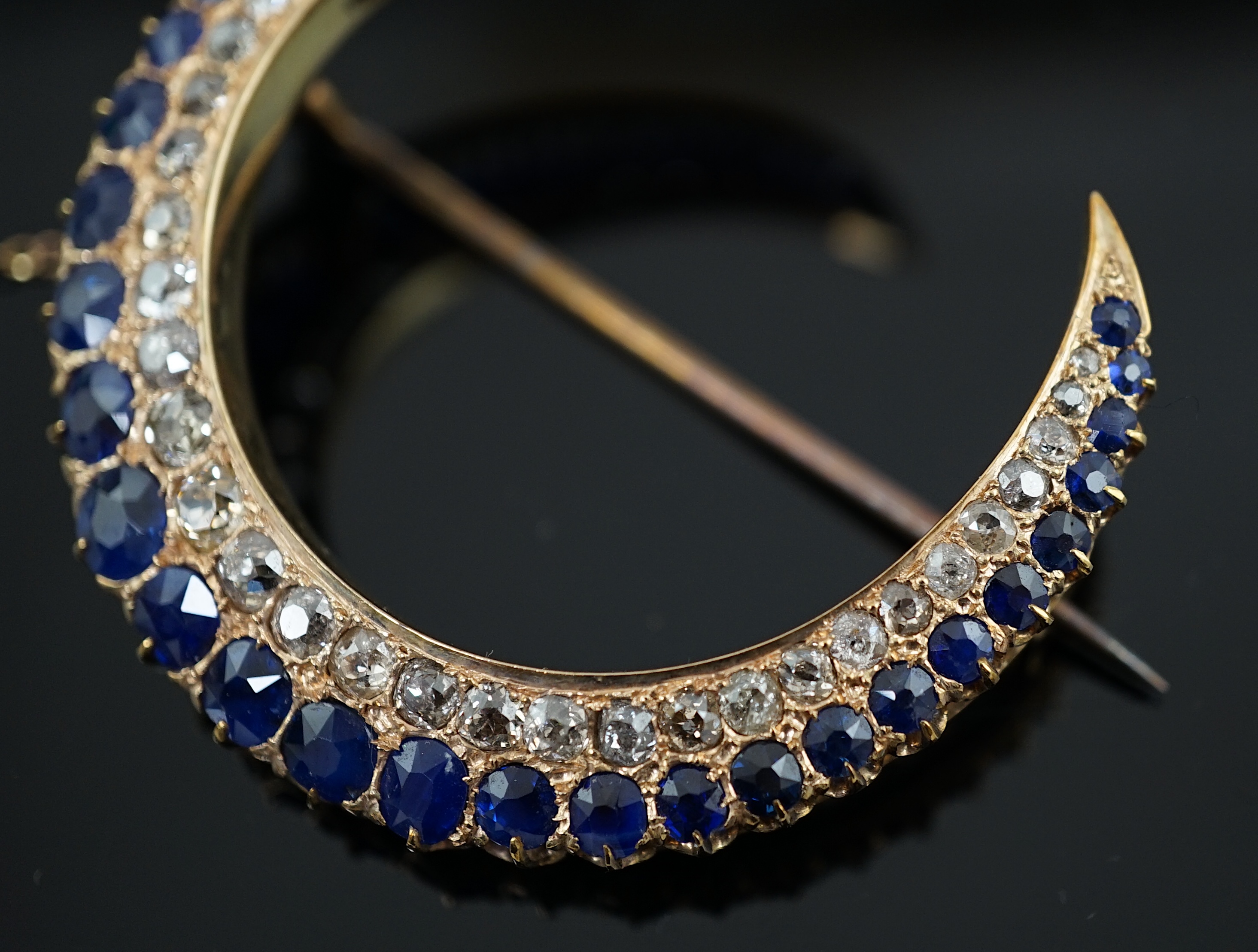 An early to mid 20th century gold, graduated sapphire and graduated diamond set two row crescent brooch
